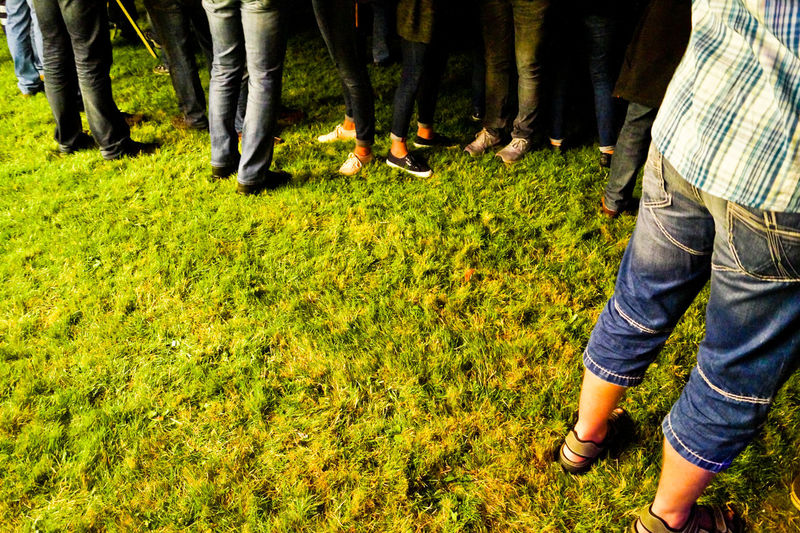 Low section of people standing on grassy field