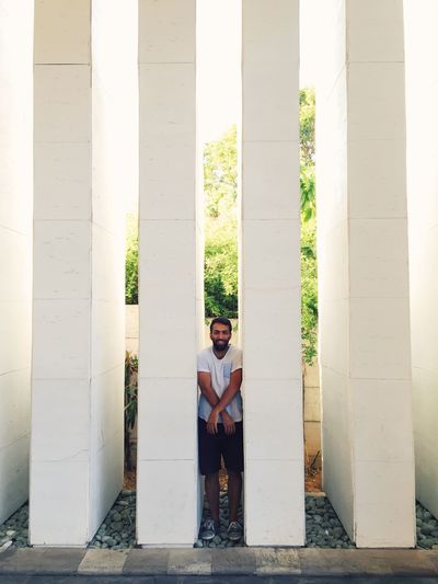 Full length portrait of man standing amidst white columns