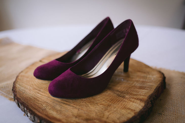 Maroon wedding shoes on top of wood round
