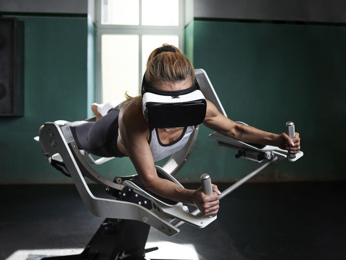 Woman wearing vr glasses using futuristic fitness machine