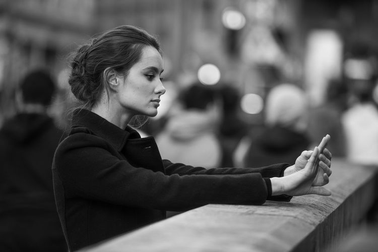 Side view of young woman using mobile phone in city