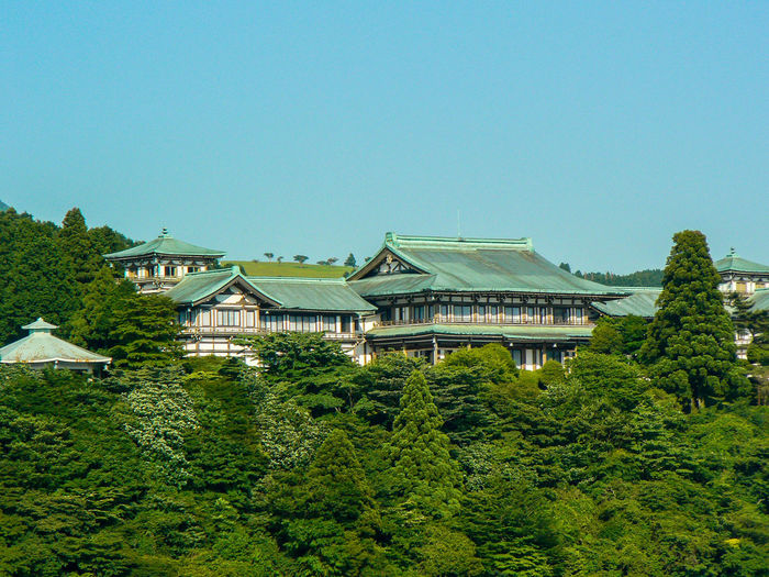 Buildings amidst trees against clear sky at hakone