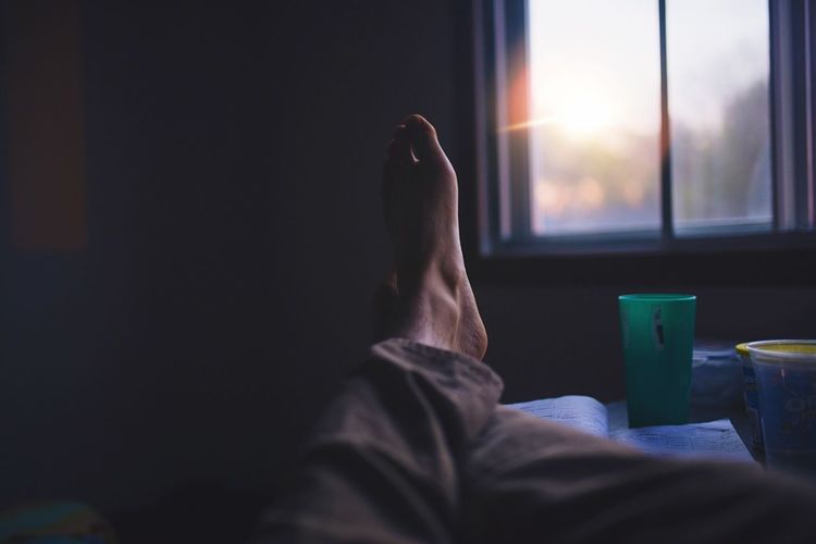 Low section of man sitting in window