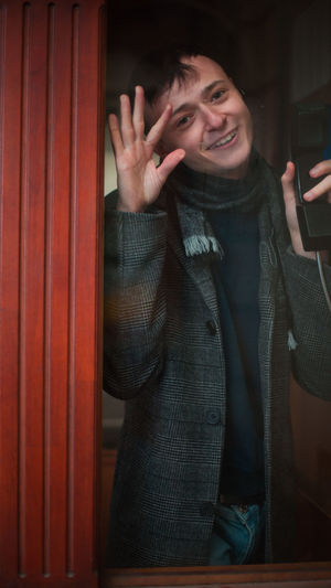 Portrait of young man seen through telephone booth
