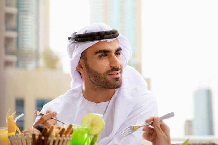 Young man wearing traditional clothing sitting at outdoor restaurant