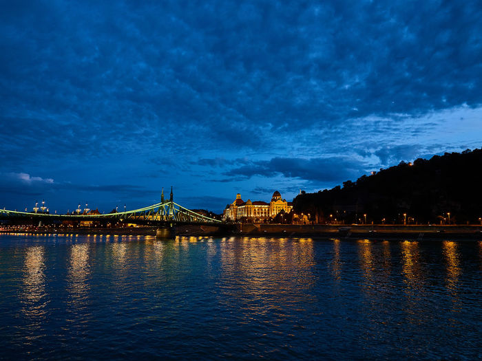Illuminated bridge over river against sky at night