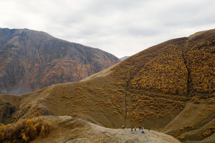 Colorful autumn landscape in cloudy weather with walking tourists. caucasus mountains, georgia.