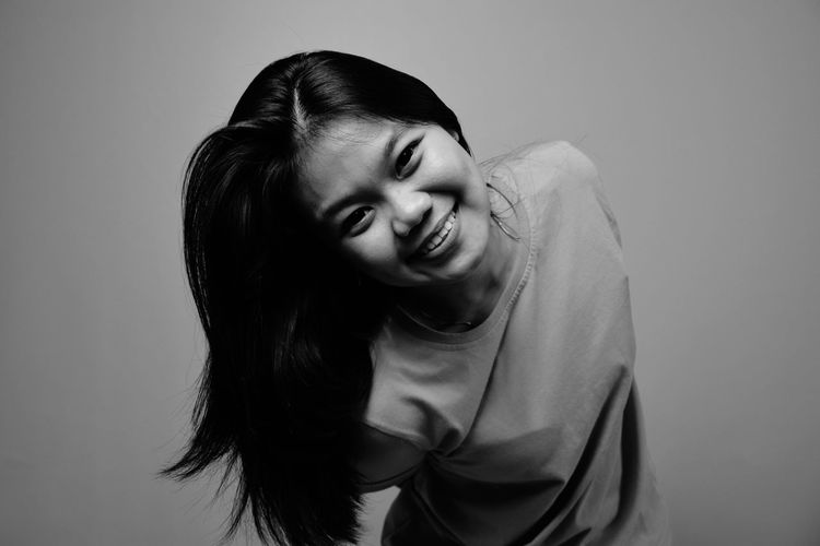 Portrait of smiling young woman against gray background