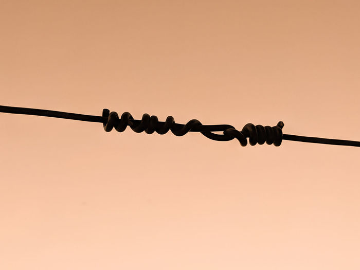Low angle view of barbed wire against clear sky
