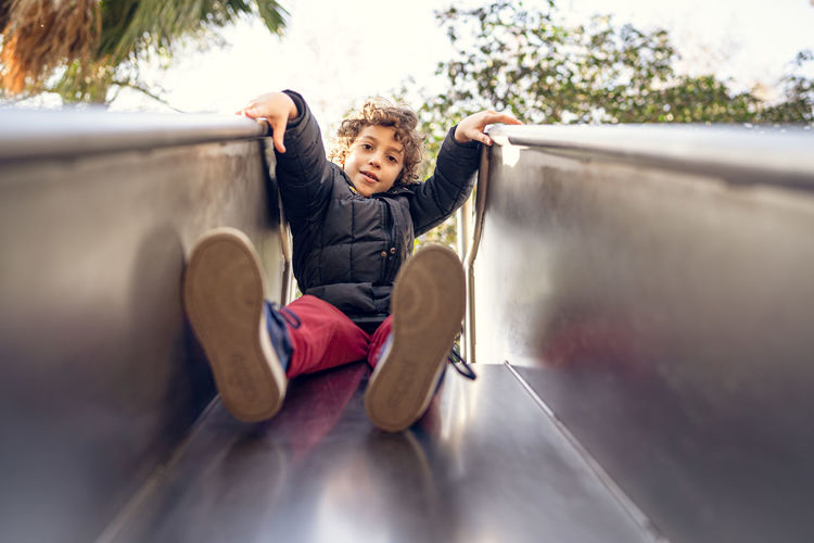 Low angle portrait of boy sitting on slide