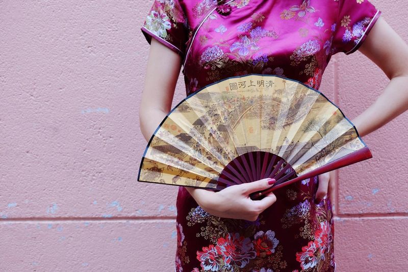 Midsection of woman holding hand fan