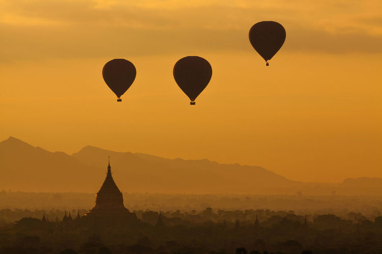 Silhouette hot air balloons flying during sunset