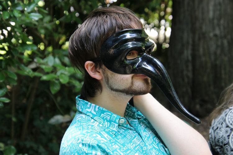 Close-up of man wearing black mask looking away outdoors