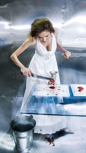 High angle view of young woman removing meat from grinder