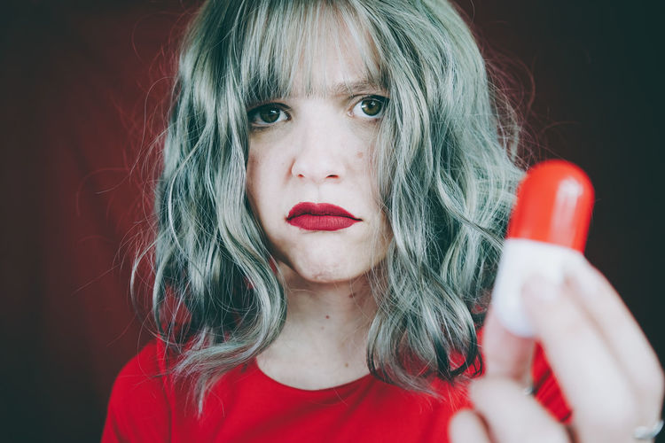 Close-up portrait of woman holding capsule