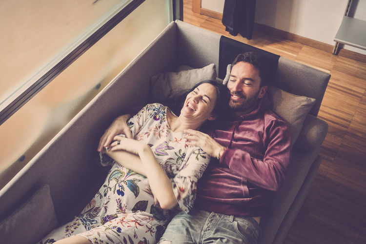 Smiling couple lying on sofa at home