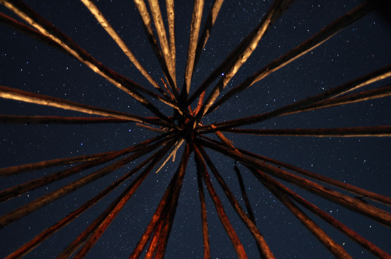 Night sky seen through teepee poles in quebec