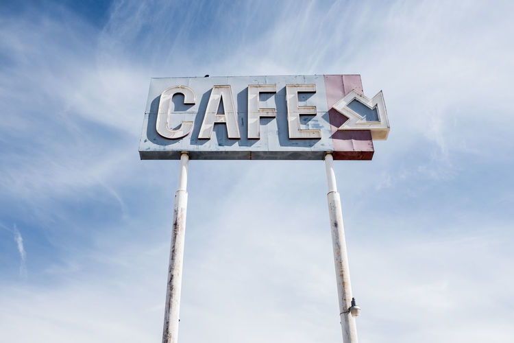 Low angle view of cafe sign against sky