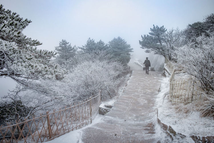 The traveler man walking on the walkway and snow cover all of the areas on the huangshan mountain.