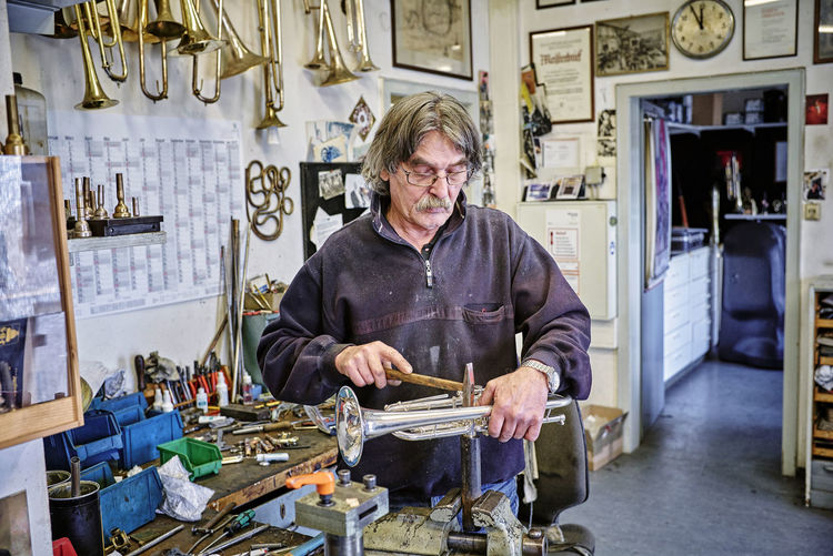 Portrait of man using mobile phone while standing in workshop