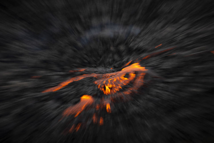 From above soft focus of fiery lava flowing through gray terrain in iceland