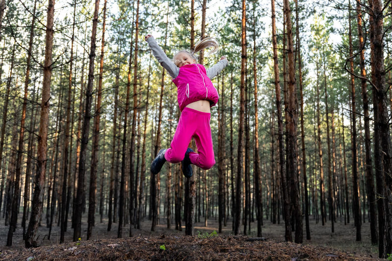 Girl jumoing against trees in forest