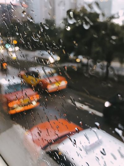 Cars on road seen through wet glass window during rainy season