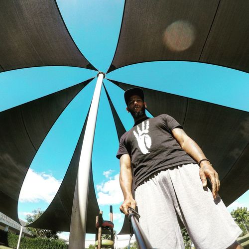 Low angle portrait of man holding monopod under sunshade