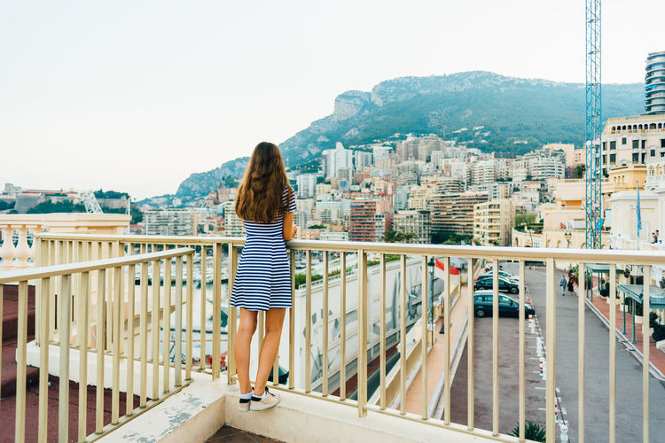 Rear view of girl standing against cityscape