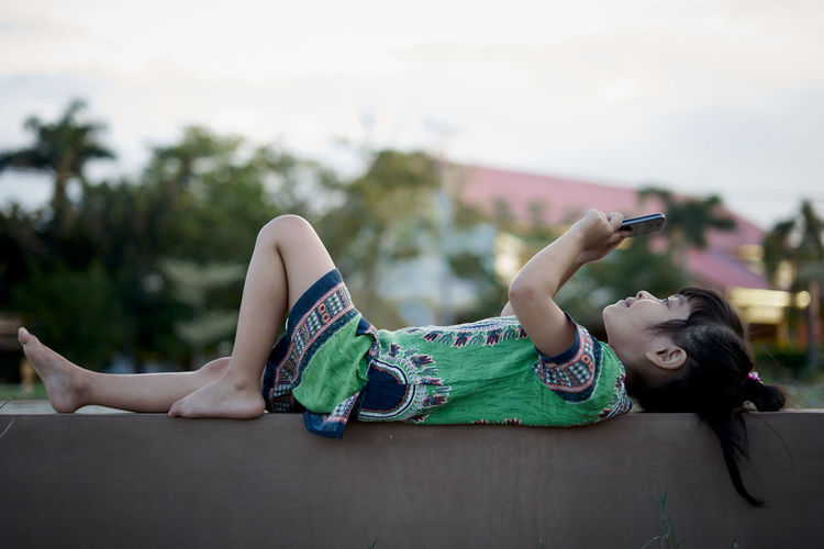 Girl using mobile phone while lying outdoors