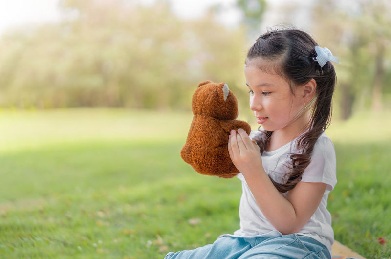Girl with toy sitting outdoors
