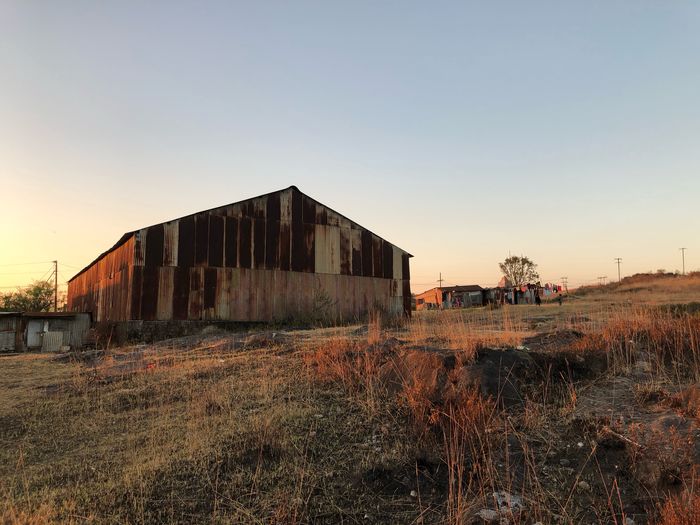 Abandoned barn on field against clear sky