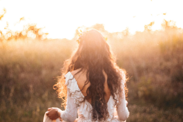 Rear view of woman wearing dress standing against sky during sunset