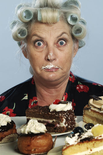 Portrait of senior woman with hair curlers and chocolate cake