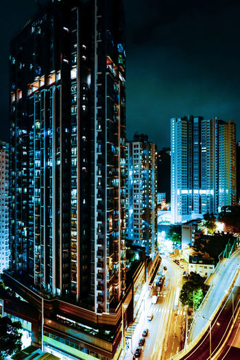 Illuminated modern buildings in city against sky at night
