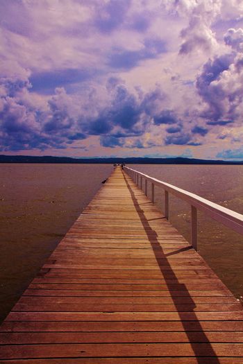 Pier on sea against cloudy sky
