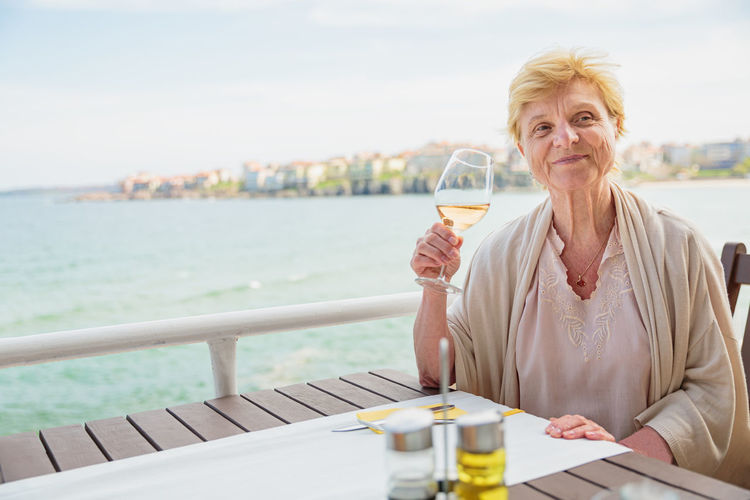 Elderly woman traveler sitting alone on the terrace of coffee shop