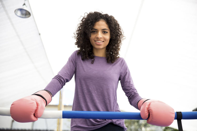 Portrait of smiling female boxer standing in boxing ring