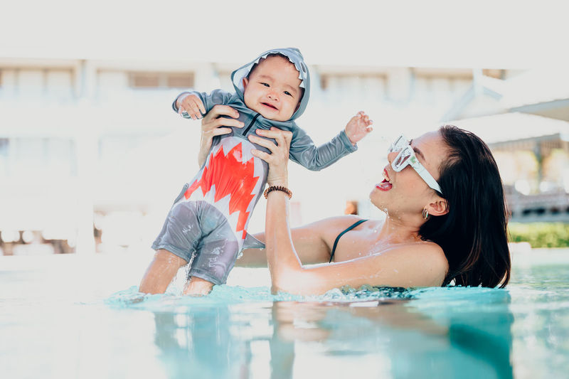 Smiling woman with son enjoying in pool