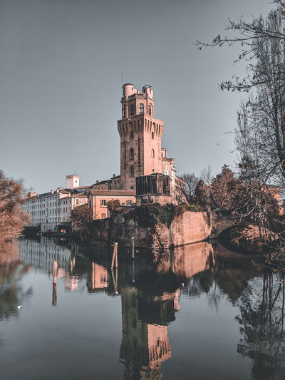 Buildings by lake against sky
