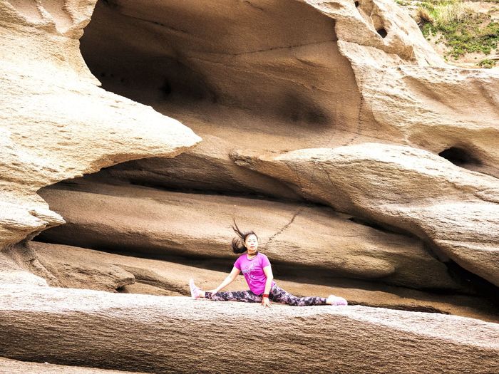 Woman doing the splits on rock formation