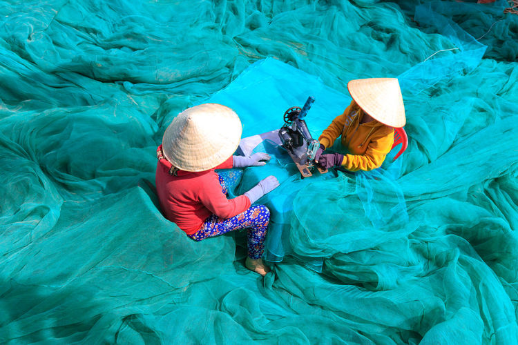 High angle view of women sewing net