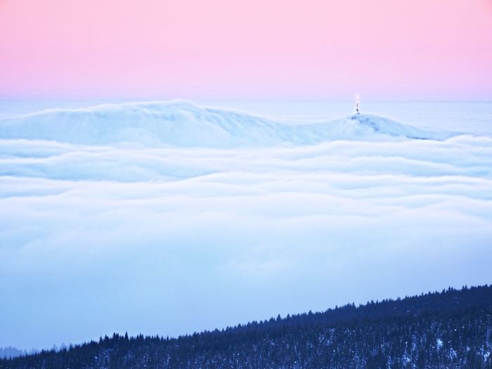 Far mountain peak with observatory above creamy mist. shinning lights on antenna. wavy fog in vallye