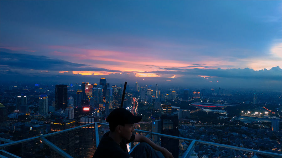 Man in illuminated city at dusk