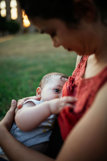 Midsection of mother nursing baby outdoors