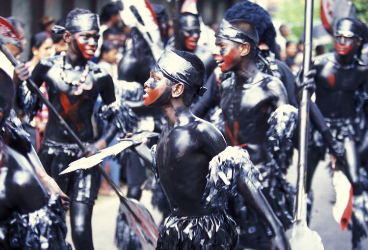 Shirtless boys with black paint on body during traditional festival