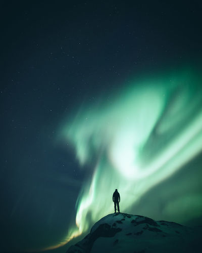 Low angle view of person standing against sky at night