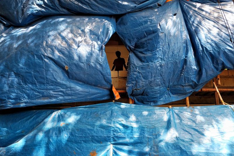 Silhouette man standing on bridge seen through tarpaulin