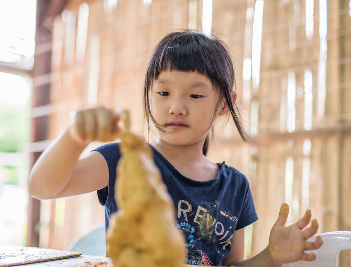 Close-up of girl making craft with mud on table