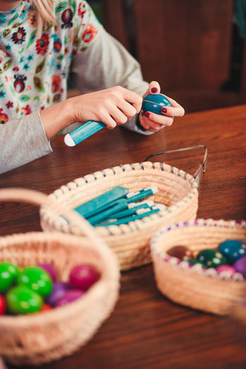 Midsection of woman making easter eggs on table